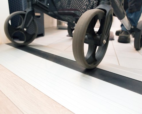 Close-up foto van de wielen van een rollator op een drempel.
