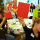 Tijdens een burgerberaad zitten deelnemers rond een tafel die groene en rode papiertjes in de lucht steken.