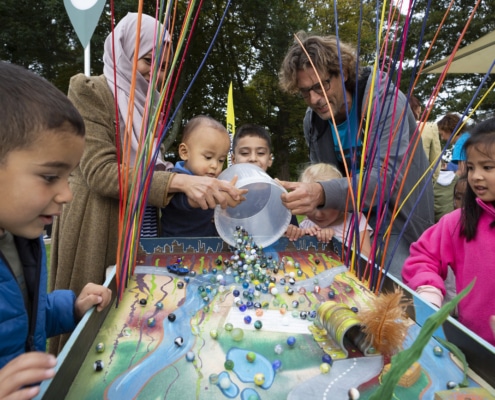 Tijdens het Escampfestival spelen kinderen met ouders met een knikkerbaan.