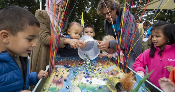 Tijdens het Escampfestival spelen kinderen met ouders met een knikkerbaan.