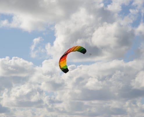 Foto van een regenboogvlieger tegen een lucht met wolken.